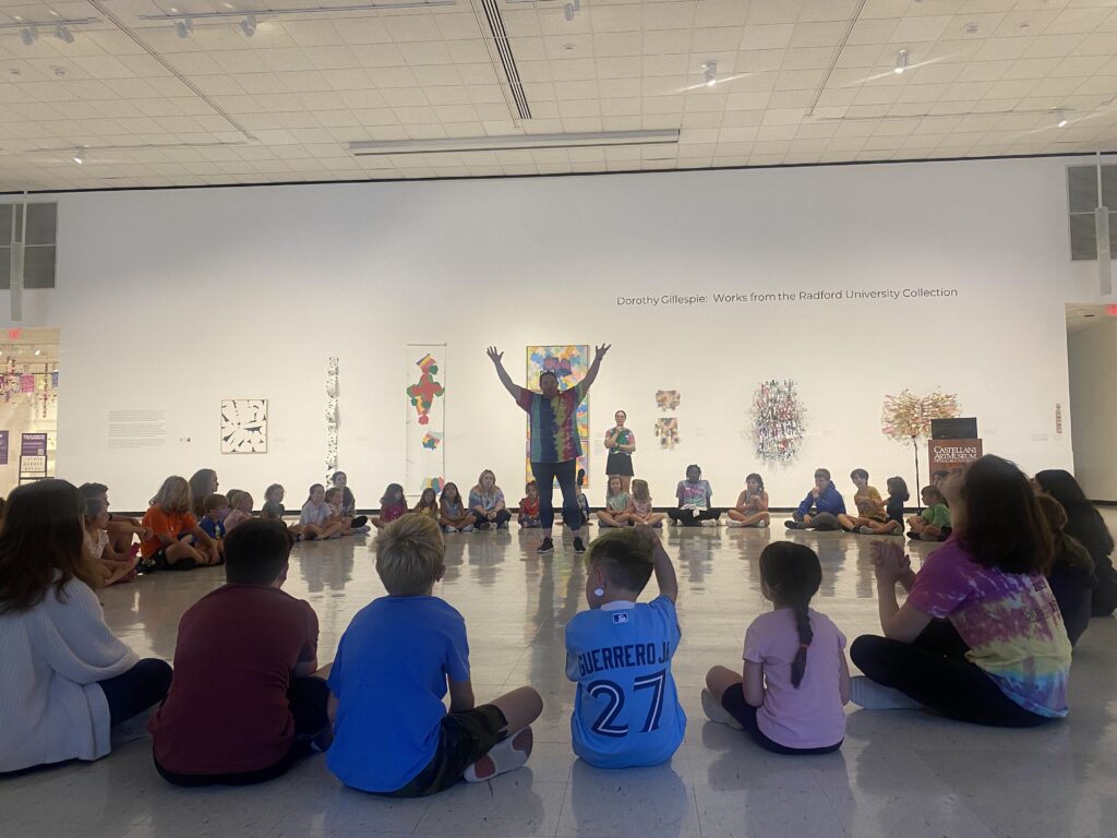 Kids sitting in a circle around a teacher in the main gallery